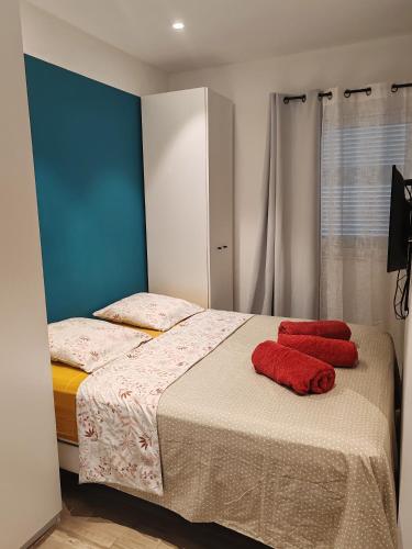 une chambre avec un lit avec deux oreillers rouges dessus dans l'établissement Appartement 80 m2 avec jardin - 50m de la plage TIKI, à Saint-Raphaël