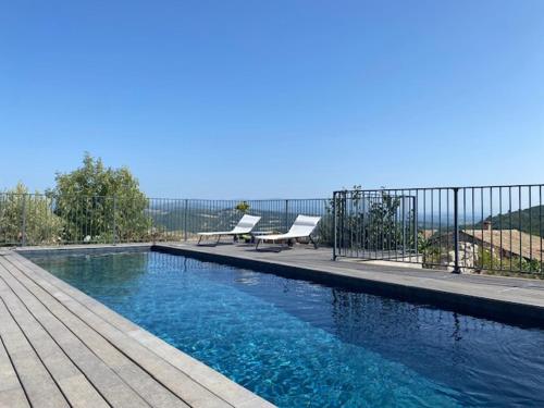 une piscine avec deux bancs à côté d'une clôture dans l'établissement Les Terrasses de Lure & piscine, à Villemus