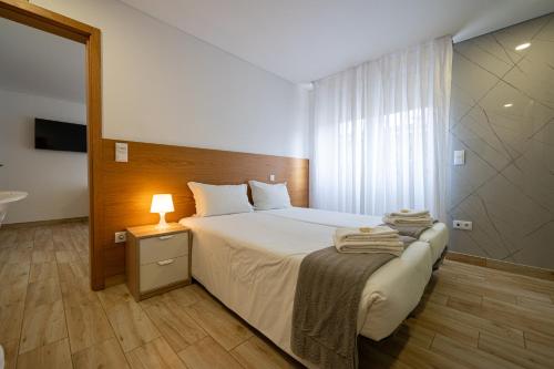 a bedroom with a bed and a lamp on a table at Central Suites in São João da Madeira