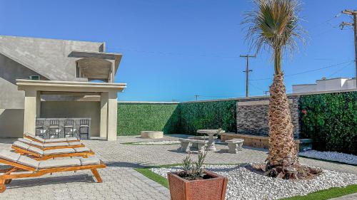 a patio with a palm tree and a table and chairs at A Wave FROM IT ALL in Las Conchas