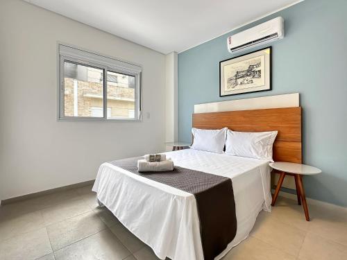 a bedroom with a large bed and a window at 100 metros da praia - Condomínio - 3 suítes - Churrasqueira in Guarujá