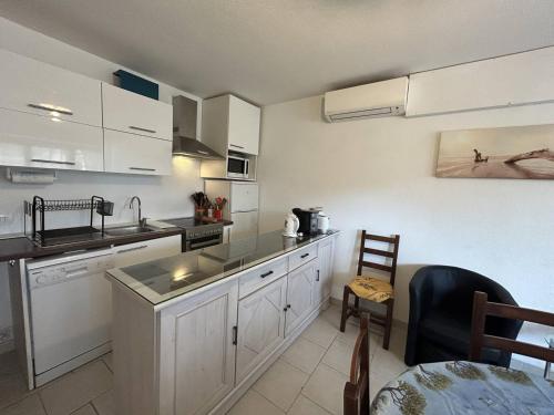 - une cuisine avec des placards blancs, un évier et une table dans l'établissement Appartement climatisé 3 pièces avec terrasse, face à la plage, parking inclus - Bormes-les-Mimosas - FR-1-251-806, à Bormes-les-Mimosas