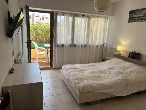 - une chambre avec un lit, une table et un balcon dans l'établissement Appartement climatisé 3 pièces avec terrasse, face à la plage, parking inclus - Bormes-les-Mimosas - FR-1-251-806, à Bormes-les-Mimosas