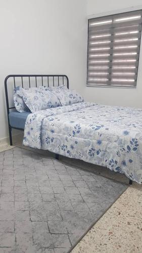 1 cama con edredón azul y blanco en un dormitorio en Aman 2 Homestay Senawang Musliim only, en Seremban