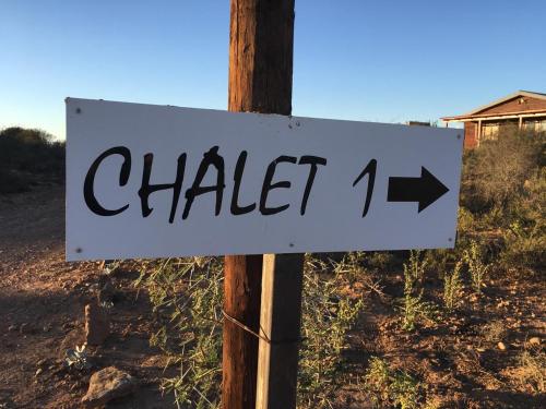 a white sign with an arrow on a pole at Klein Karoo Game Lodge in Oudtshoorn