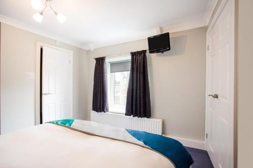a bedroom with a bed and a television on the wall at The Village Inn, Murton Seaham in Murton