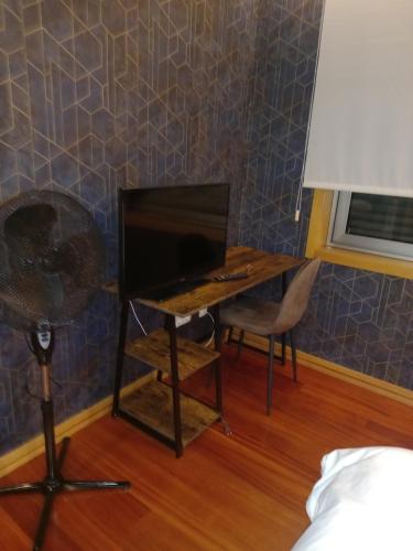 a desk with a television and a chair in a room at Com o Douro à vista in Jovim