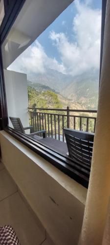 a balcony with chairs and a view of the mountains at Mountain Heaven Mcleodganj in Dharmsala