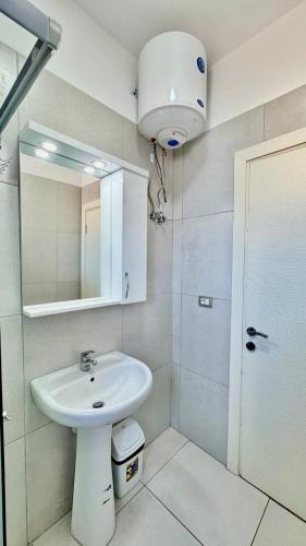 un bagno bianco con lavandino e specchio di Corfu View Apartment a Sarandë