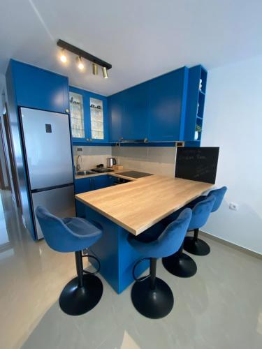 a blue kitchen with a wooden table and blue chairs at Viridian Three Apartment, VALJEVO in Valjevo