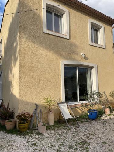 une chaise assise à l'extérieur d'une maison avec des plantes en pot dans l'établissement Chambre privée en Provence, à Villeneuve-lès-Avignon