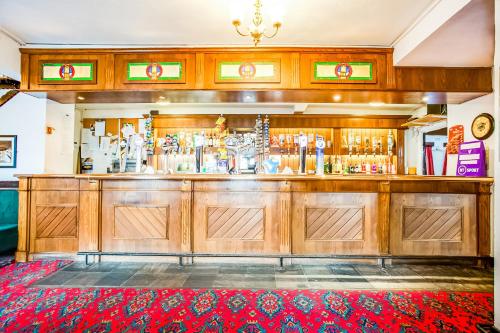 a bar with wooden cabinets and a red rug at The Village Inn, Murton Seaham in Murton