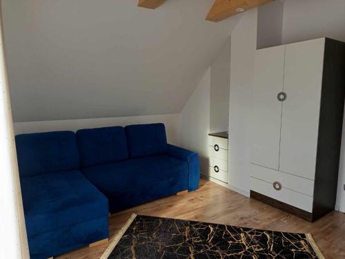 a blue couch in a room with a white cabinet at Domek pod lasem in Toporzysko