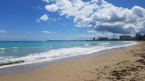a beach with the ocean and buildings in the background at IVT Condo in San Juan