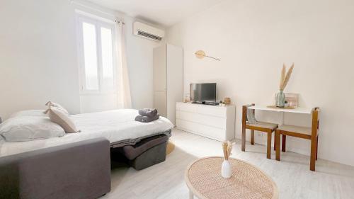une chambre blanche avec un lit et une table dans l'établissement La Bella Niçoise, à Nice