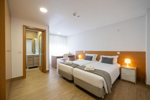 a bedroom with a large bed and a bathroom at Central Suites 3 in São João da Madeira
