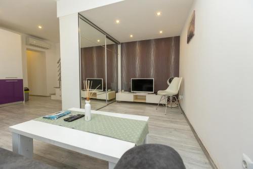 a living room with a white bench and a television at Alpha loft 1BR apartment in center in Zadar