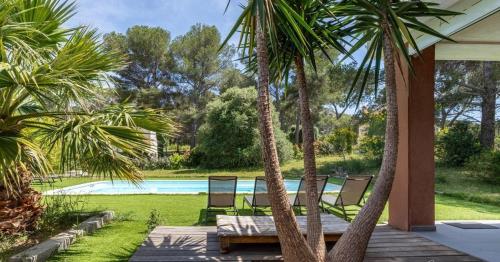 une terrasse avec deux palmiers et une piscine dans l'établissement Villa Cap Dramont, à Saint-Raphaël