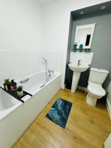 a bathroom with a tub and a toilet and a sink at Modern Economy Glasgow Apartment with King bed in Glasgow