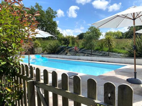piscina con ombrellone e recinzione di Chambres d'hôtes Maison Narbay aux portes du pays Basque a Saint-André-de-Seignanx
