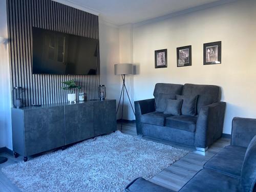 a living room with a couch and a television at Glasgow Apartment close to the airport in Renfrew