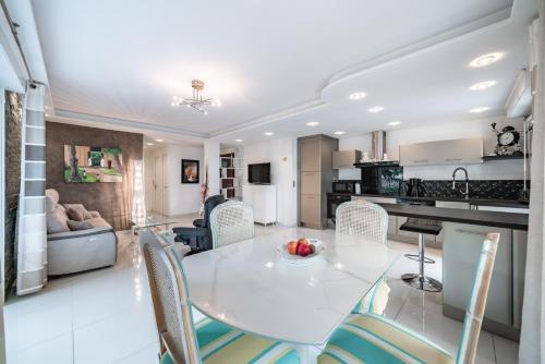 une cuisine et un salon avec une table et des chaises blanches dans l'établissement 3 pièces au calme avec terrasses et verdure, à Cannes