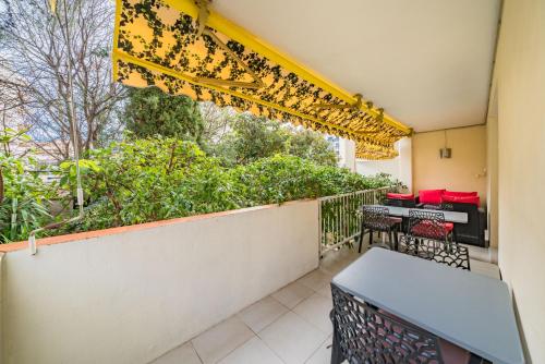un balcon avec une table, des chaises et une fenêtre dans l'établissement 3 pièces au calme avec terrasses et verdure, à Cannes
