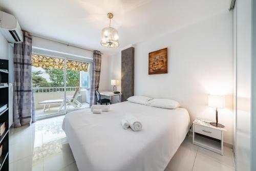 une chambre blanche avec un lit et un balcon dans l'établissement 3 pièces au calme avec terrasses et verdure, à Cannes