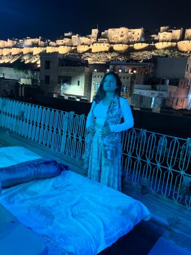 una donna che di notte si alza in piedi su un balcone di Mirvana Guest House & Camel safari a Jaisalmer