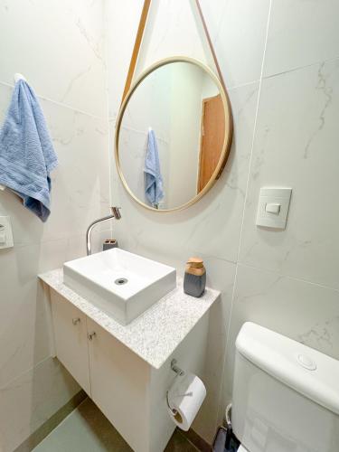 a white bathroom with a sink and a mirror at Apartamento 1 quarto Jardim da Penha in Vitória