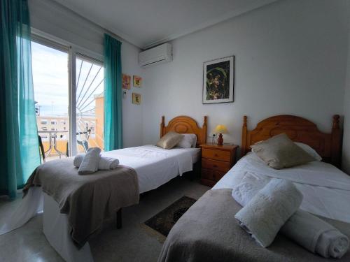 a bedroom with two beds and a large window at Bungalow Malibu Complex Doa Pepa- Rojales in Ciudad Quesada