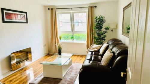 a living room with a leather couch and a fireplace at Modern 2 Bedroom GF - Aberdeen City Centre - Private Car Park in Aberdeen