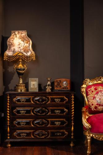 a dresser with a lamp on top of it next to a chair at The Harrison Chambers of Distinction in Belfast