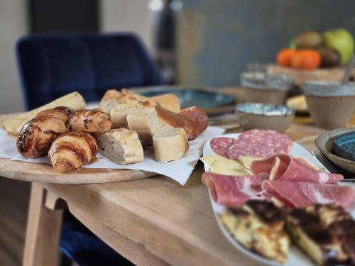 a table topped with different types of bread and meats at La Ferme de la Cour in Herbeumont