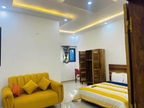 Résidences hôtels sibontour في ياموسوكرو: غرفة نوم بسرير واريكة صفراء