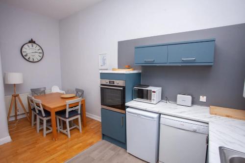 a kitchen with blue cabinets and a table and a clock at Newly Renovated Flat in Trendy Finnieston in Glasgow