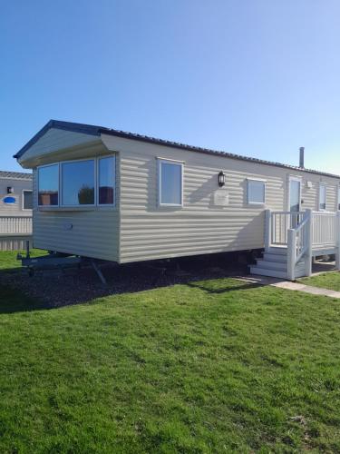 a white mobile home with a porch on a yard at L90 HOLIDAY HOMe in Mablethorpe