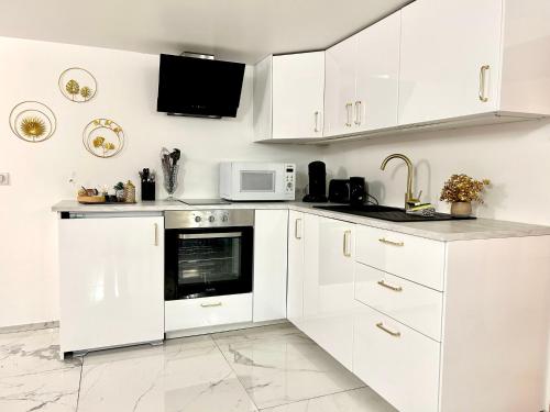 une cuisine blanche avec des armoires blanches et un micro-ondes dans l'établissement Ti Dous - Terrasse, Jardin, Proche Centre ville, au Faouët