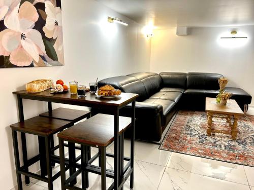 a living room with a black leather couch and a table at Ti Dous - Terrasse, Jardin, Proche Centre ville in Le Faouët