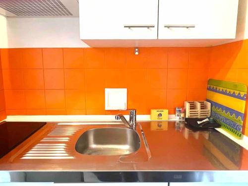 - une cuisine avec un évier et un mur orange dans l'établissement M20 Marquer Superbe t2 Gare Annemasse, à Annemasse