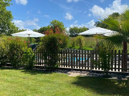 une clôture en bois avec deux parasols au-dessus dans l'établissement Chambres d'hôtes Maison Narbay aux portes du pays Basque, à Saint-André-de-Seignanx