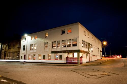 a large white building on a street at night at The Crown Inn in Stornoway