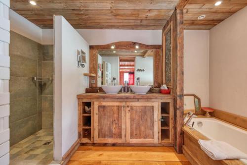 une salle de bain avec deux lavabos, une baignoire et une douche dans l'établissement Chalet Foret Rouge, à Chamonix-Mont-Blanc
