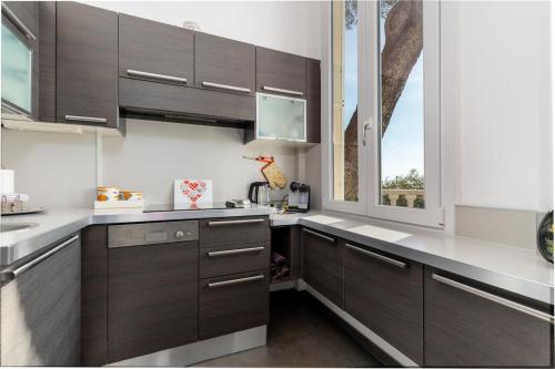 une cuisine avec des placards brun foncé et une fenêtre dans l'établissement Les Floralies, large 3-room, sea and Monaco view, à Roquebrune-Cap-Martin