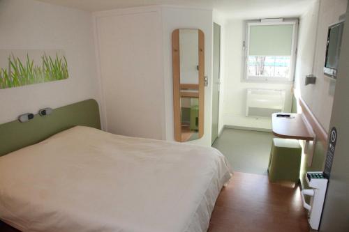 a small bedroom with a bed and a mirror at Hotel Ibis Budget Nice Palais Nikaia in Nice