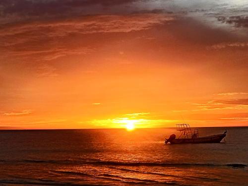 a boat sitting in the ocean at sunset at Arte Sano Hotel Only Adults - Near Beach in Holbox Island