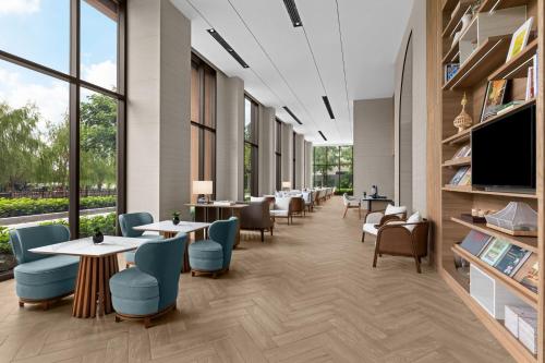 a waiting room with tables and chairs and a flat screen tv at Courtyard by Marriott Bangkok Suvarnabhumi Airport in Lat Krabang