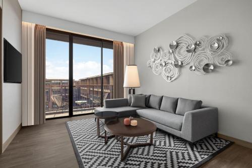 a living room with a couch and a large window at Courtyard by Marriott Bangkok Suvarnabhumi Airport in Lat Krabang