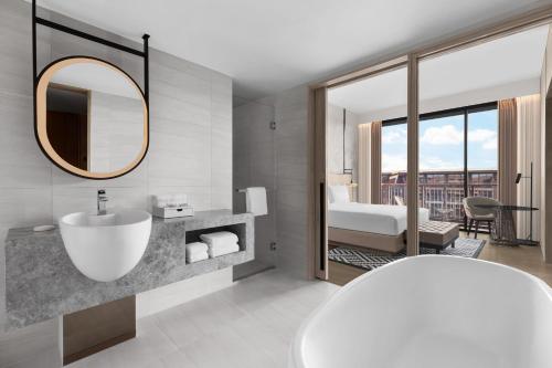 a bathroom with a tub and a sink and a mirror at Courtyard by Marriott Bangkok Suvarnabhumi Airport in Lat Krabang