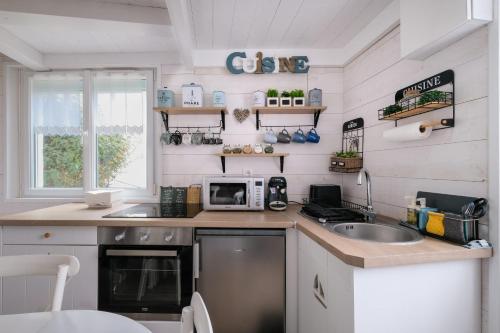 une petite cuisine avec un évier et un micro-ondes dans l'établissement La Mamy - Wi-fi - 400m plage, à Pornichet